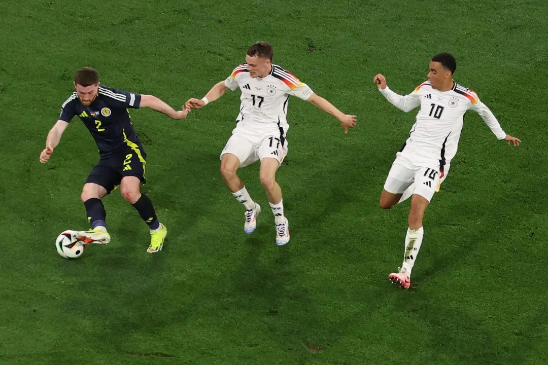 (i-d) El jugador escoc&eacute;s Anthony Ralston en acci&oacute;n contra los alemanes Florian Wirtz y Jamal Musiala de Alemania durante el partido de la Eurocopa 2024 entre Alemania y Escocia en Munich, Alemania. EFE/EPA/MOHAMED MESSARA