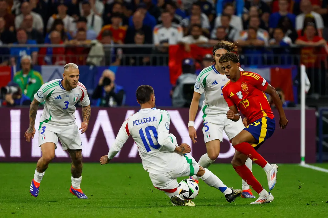 El delantero de la selecci&oacute;n espa&ntilde;ola de f&uacute;tbol Lamine Yamal (d) pelea un bal&oacute;n con Lorenzo Pellegrini (2i), de la selecci&oacute;n italiana, durante el encuentro de la fase de grupos de la Eurocopa 2024 en el Arena AufSchalke, Gelsenkirchen (Alemania). EFE//JJ Guill&eacute;n