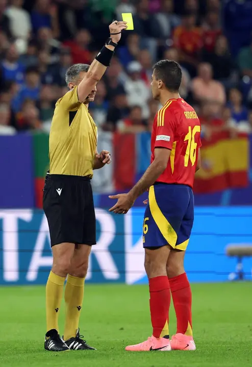 Referee Slavko Vincic (L) muestra amarlla a Rodrigo Hern&aacute;ndez, centrocampista de la selecci&oacute;n espa&ntilde;ola en Gelsenkirchen. Alemania. EFE/EPA/CHRISTOPHER NEUNDORF