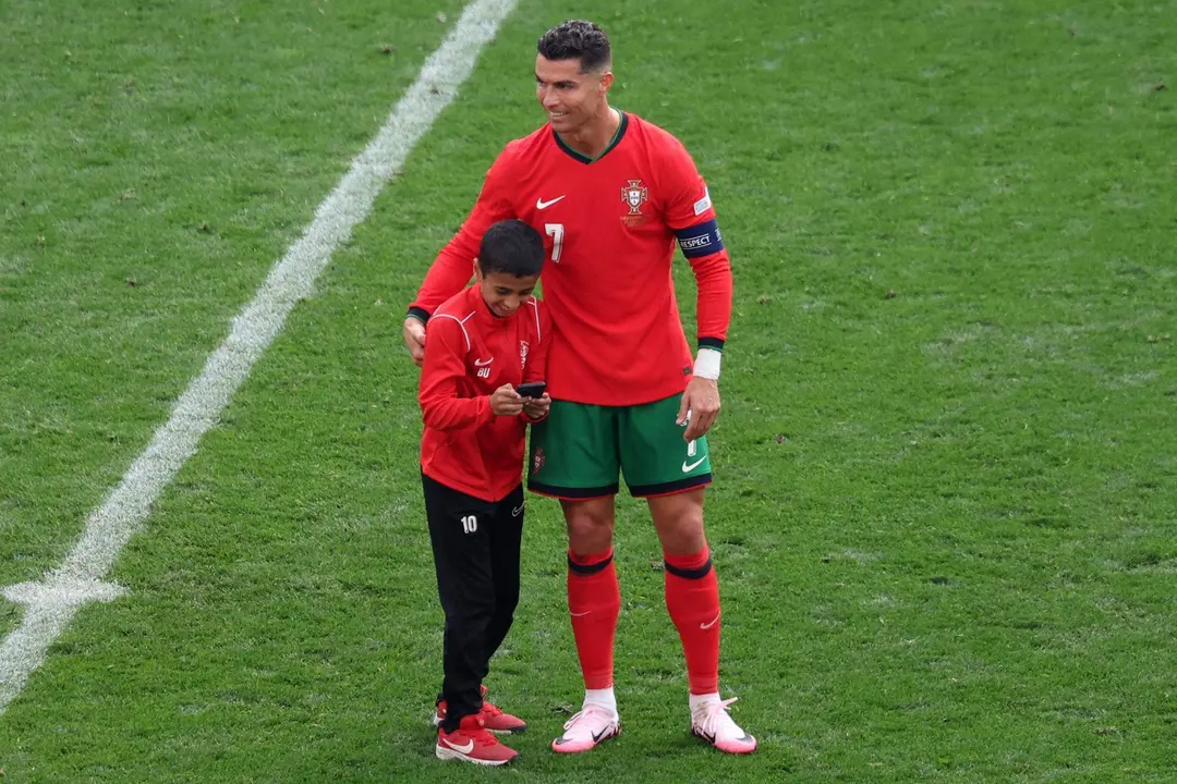 El jugador portugu&eacute;s Cristiano Ronaldo abraza a un ni&ntilde;o en el campo durante el partido de f&uacute;tbol del grupo F de la Euroco&agrave; 2024 entre Turqu&iacute;a y Portugal, en Dortmund, Alemania, .EFE/EPA/CHRISTOPHER NEUNDORF